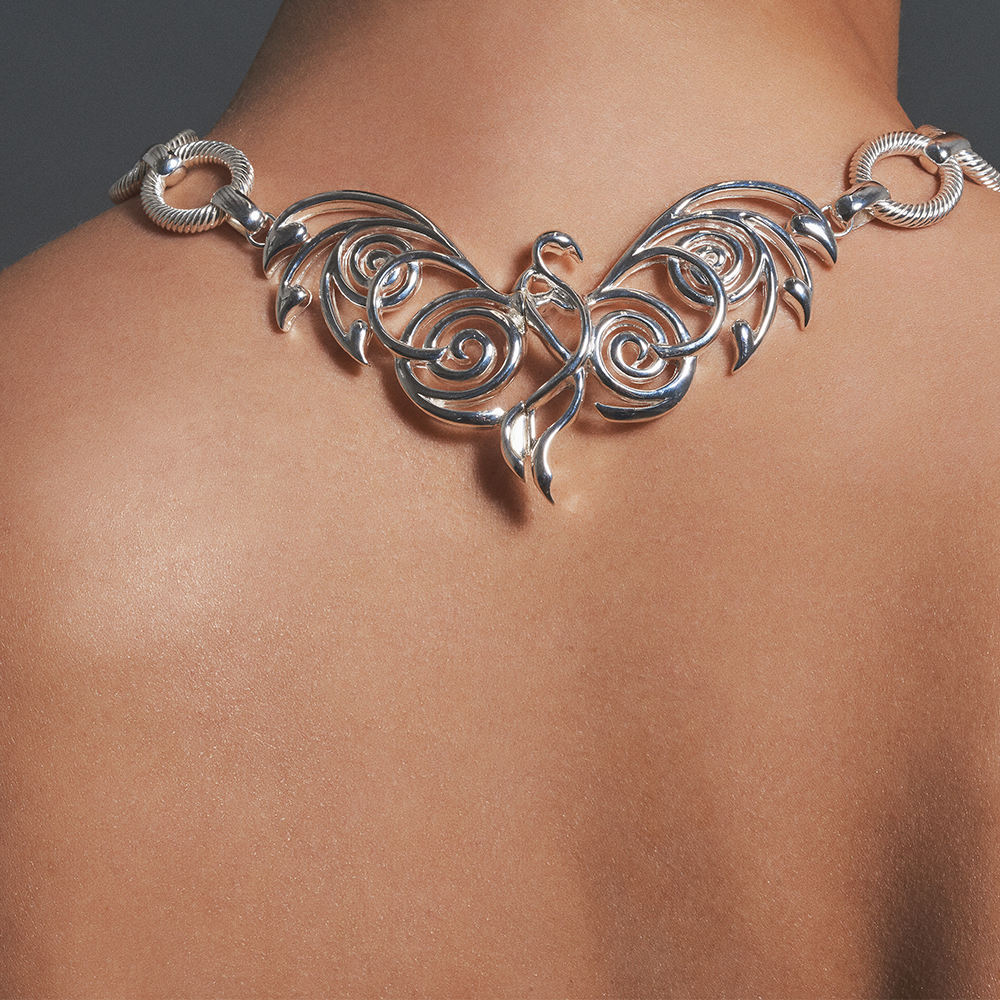 The detailed back clasp depicts a phoenix, a mythological bird with multiple meanings.