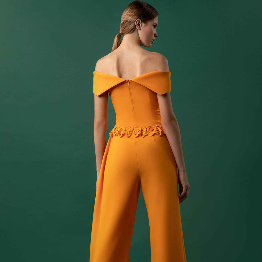 Off shoulder draped crepe top with guipure added on the hemline, and flared crepe pants with drapery slit on the side.