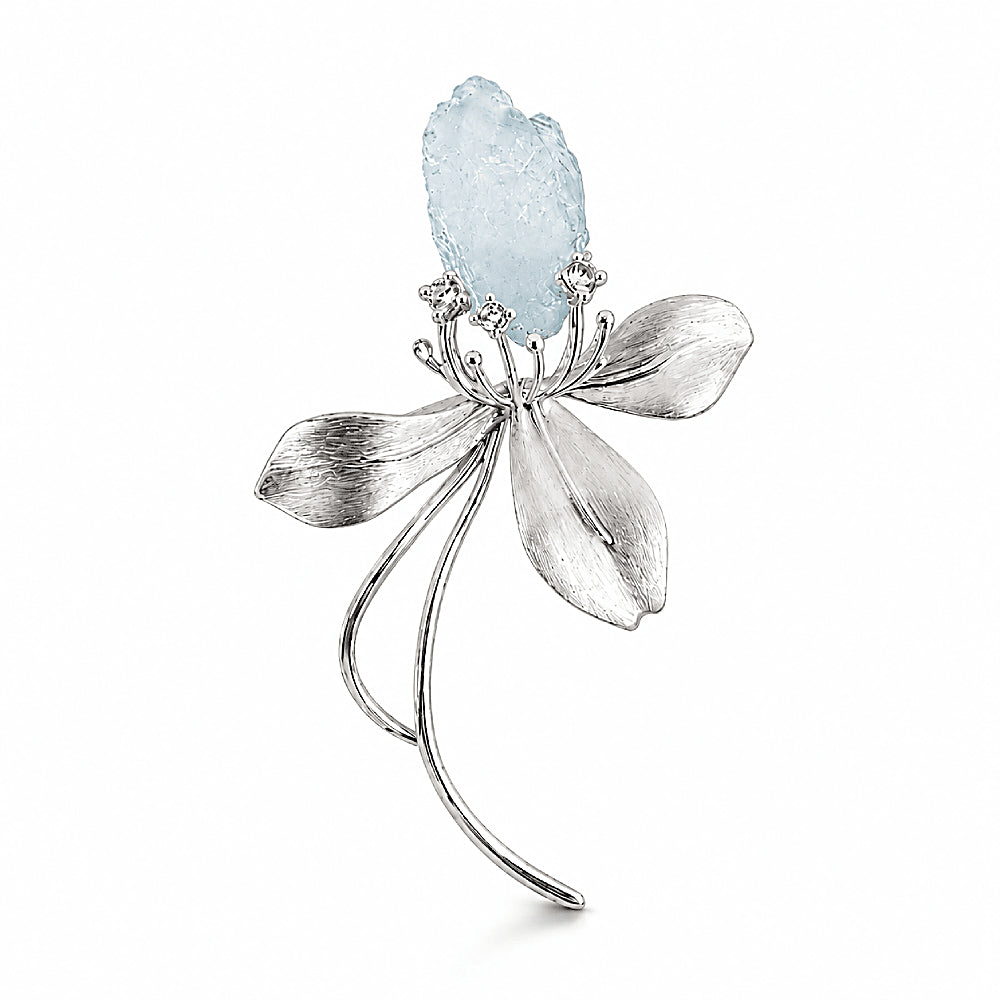 Discover the Wild Iris Silver & Aquamarine Brooch at The Luxe Maison, featuring a raw aquamarine crystal set in sculptural silver petals, with a versatile design that can also be worn as a pendant.