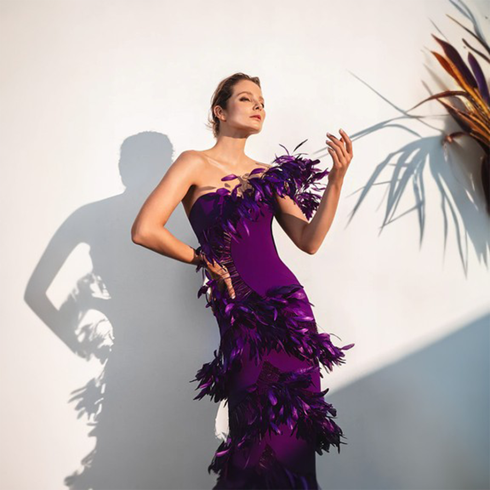 An asymmetric dress in purple silk crepe and ruffled plumes.